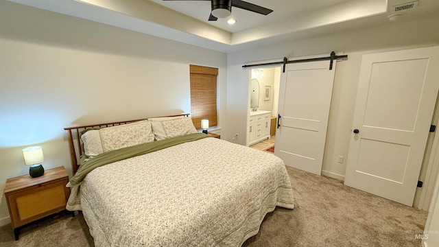 bedroom featuring connected bathroom, carpet floors, ceiling fan, a raised ceiling, and a barn door