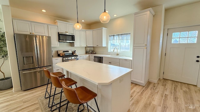 kitchen with white cabinetry, appliances with stainless steel finishes, a kitchen island, and pendant lighting