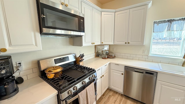 kitchen featuring sink, light hardwood / wood-style flooring, stainless steel appliances, and white cabinets