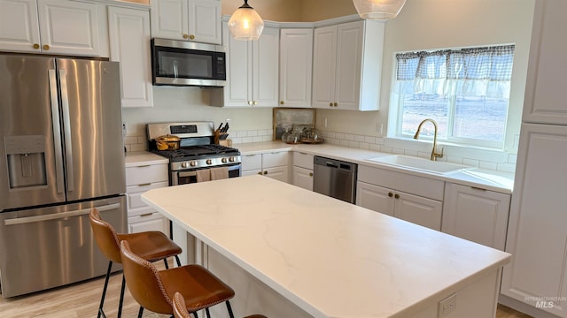 kitchen with pendant lighting, white cabinetry, stainless steel appliances, and sink