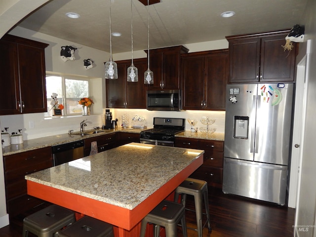 kitchen featuring sink, stainless steel appliances, a center island, a kitchen breakfast bar, and light stone countertops