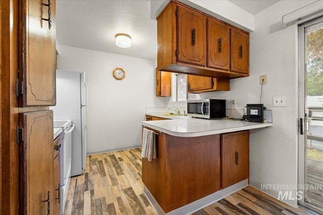 kitchen featuring kitchen peninsula, light hardwood / wood-style flooring, white electric stove, and sink