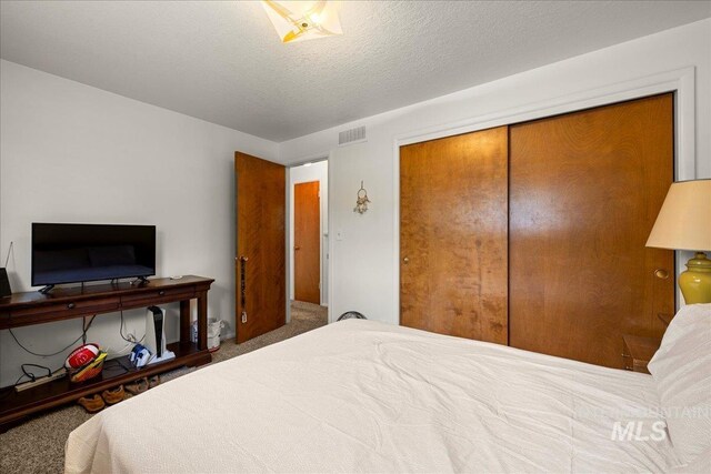 bedroom with a textured ceiling, carpet, and a closet