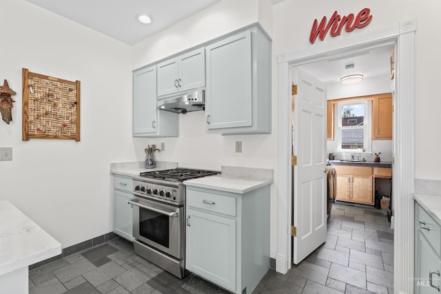 1416 N 13th St, Boise, ID 83702 - kitchen with high end stainless steel range, a sink, stone tile floors, baseboards, and under cabinet range hood