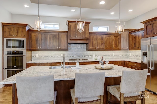 kitchen featuring stainless steel appliances, a kitchen island with sink, and pendant lighting