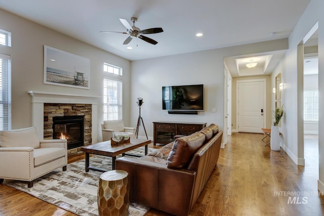 living room with a fireplace, light hardwood / wood-style flooring, and ceiling fan