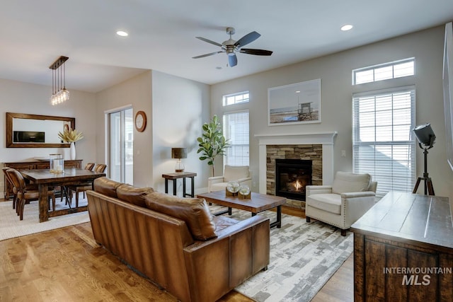 living room with ceiling fan, a fireplace, and light wood-type flooring