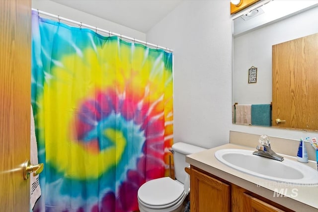 bathroom with curtained shower, vanity, and toilet