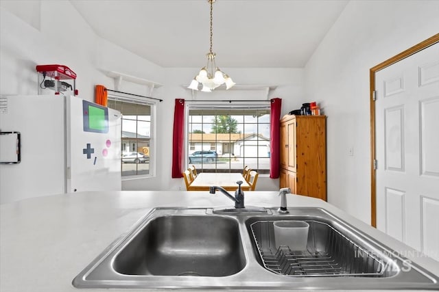 kitchen with pendant lighting, a notable chandelier, lofted ceiling, and sink