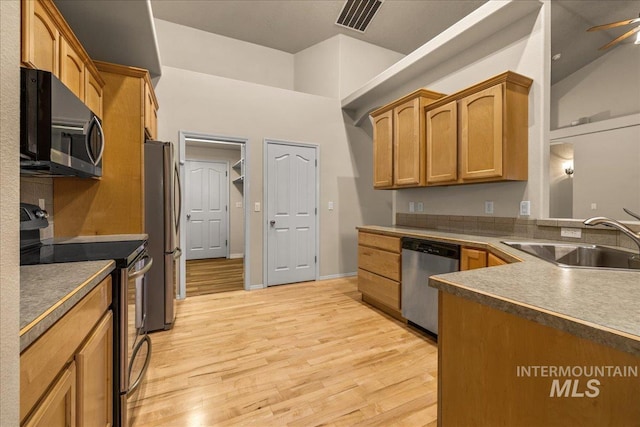 kitchen with appliances with stainless steel finishes, a sink, and light wood finished floors