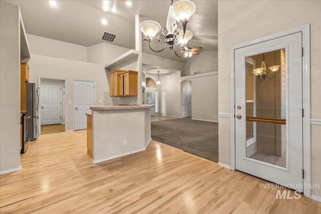 kitchen featuring a chandelier, freestanding refrigerator, lofted ceiling, light wood finished floors, and baseboards