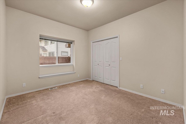 unfurnished bedroom with carpet floors, baseboards, and a closet