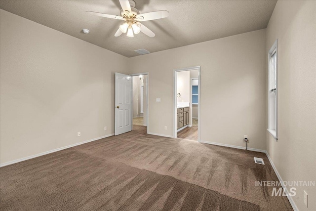unfurnished bedroom with carpet floors, baseboards, connected bathroom, a textured ceiling, and a ceiling fan