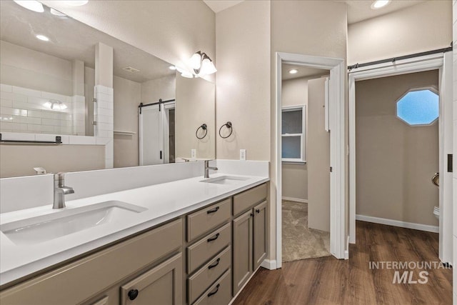 bathroom featuring wood finished floors, double vanity, recessed lighting, a shower, and baseboards