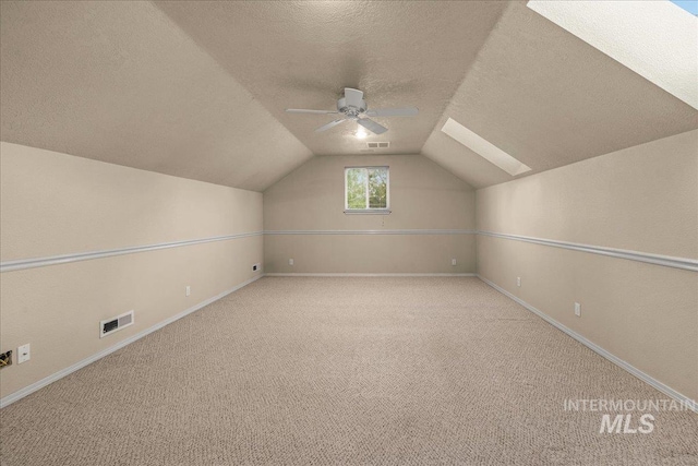 additional living space featuring a textured ceiling, ceiling fan, carpet floors, baseboards, and lofted ceiling