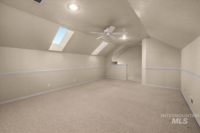 bonus room with a skylight, a textured ceiling, carpet flooring, vaulted ceiling, and baseboards