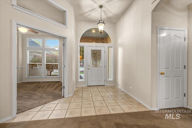 entryway with light carpet, light tile patterned floors, baseboards, and a ceiling fan