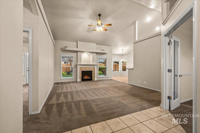 unfurnished living room featuring carpet, a ceiling fan, tile patterned flooring, baseboards, and a fireplace