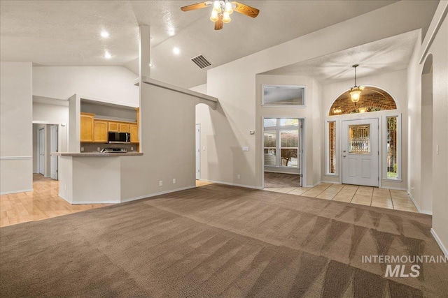 unfurnished living room featuring light colored carpet, arched walkways, high vaulted ceiling, a ceiling fan, and baseboards