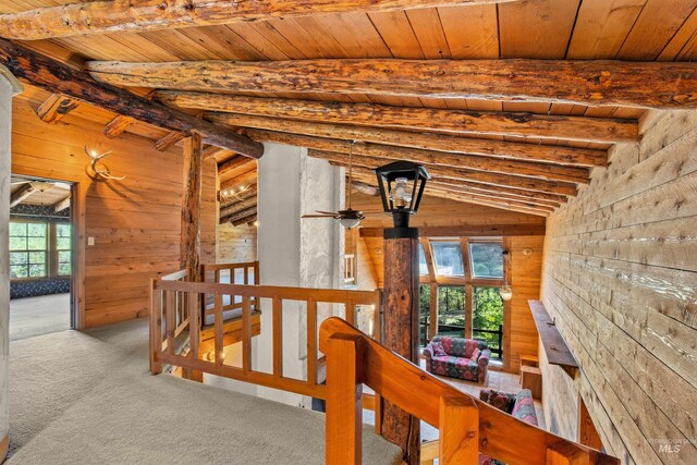 unfurnished living room featuring wood walls, ceiling fan, carpet, and wooden ceiling