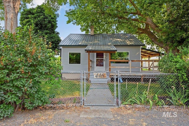 view of front facade featuring metal roof, fence, and a gate