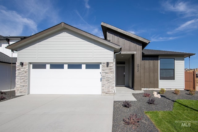 view of front of property featuring a garage, stone siding, and driveway