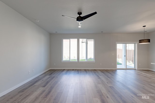 empty room featuring ceiling fan, baseboards, and wood finished floors