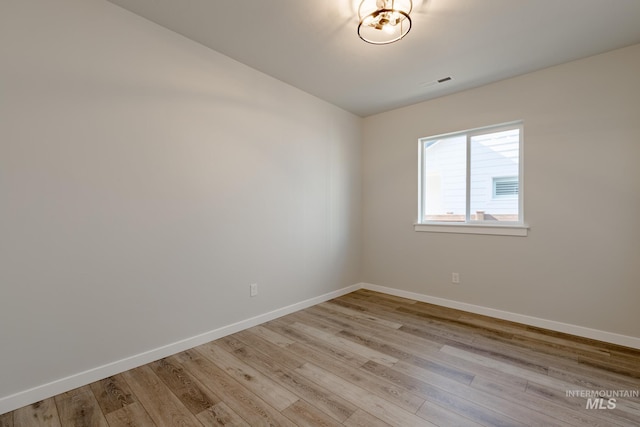 spare room featuring baseboards, visible vents, and light wood-style floors