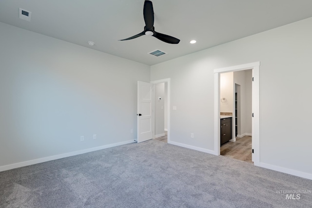 unfurnished bedroom featuring ensuite bathroom, recessed lighting, light colored carpet, visible vents, and baseboards