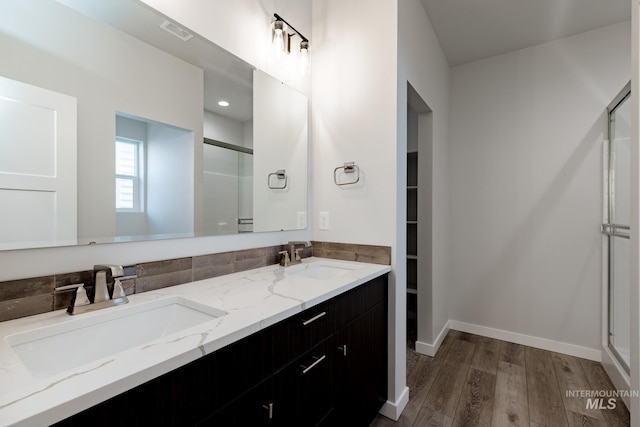 full bathroom featuring wood finished floors, a sink, visible vents, and a shower stall