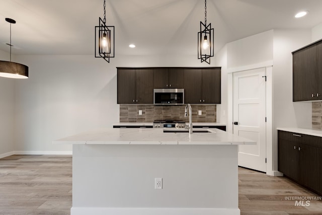 kitchen featuring light wood-type flooring, stainless steel microwave, a sink, and dark brown cabinetry