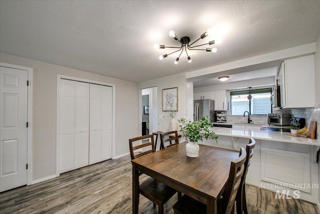 3017 S Windstream Ln, Boise, ID 83706 - dining room with a chandelier, wood finished floors, a textured ceiling, and baseboards