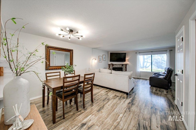3017 S Windstream Ln, Boise, ID 83706 - dining room with light wood finished floors, baseboards, a fireplace, and a textured ceiling