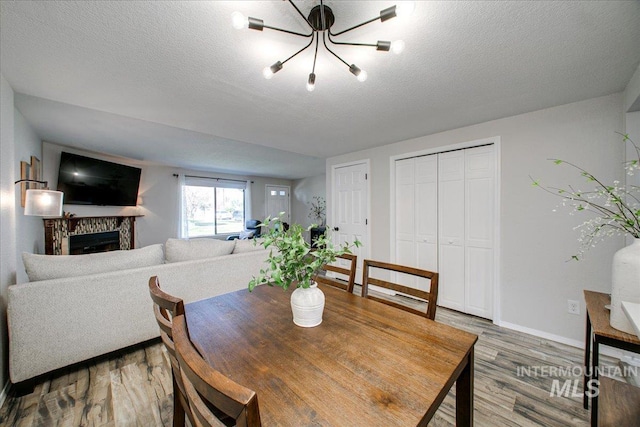 3017 S Windstream Ln, Boise, ID 83706 - dining space with light wood-style flooring, baseboards, a fireplace, a chandelier, and a textured ceiling