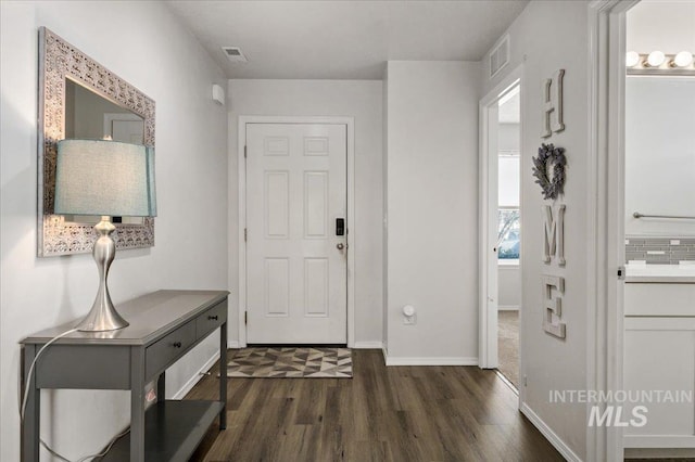 foyer featuring dark wood finished floors, visible vents, and baseboards