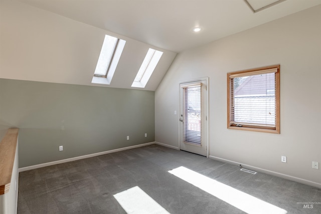 additional living space with vaulted ceiling with skylight, carpet floors, baseboards, and visible vents