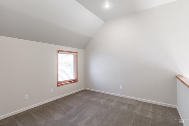 unfurnished room featuring carpet floors, baseboards, and vaulted ceiling