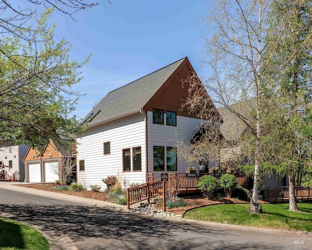view of front facade with a garage, a deck, and a shingled roof