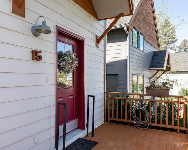 view of exterior entry with roof with shingles