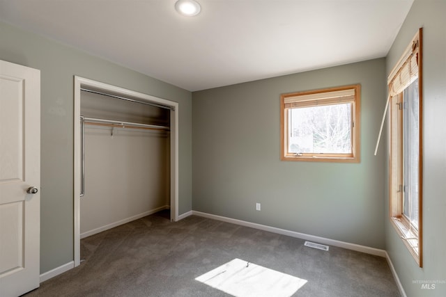 unfurnished bedroom with carpet flooring, baseboards, visible vents, and a closet