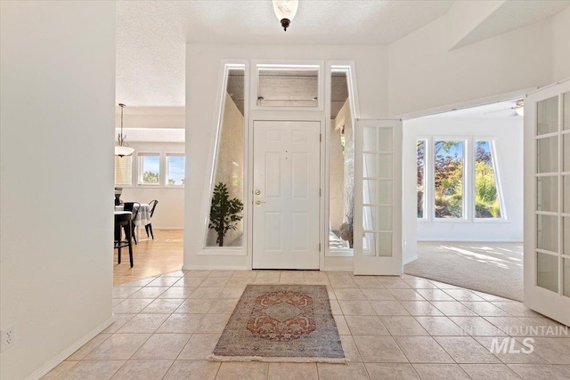 foyer featuring a healthy amount of sunlight, tile patterned floors, baseboards, and french doors