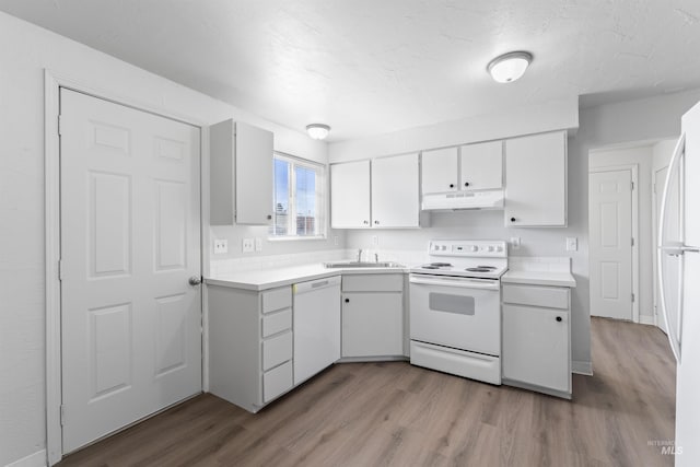 kitchen with white appliances, under cabinet range hood, light countertops, and wood finished floors