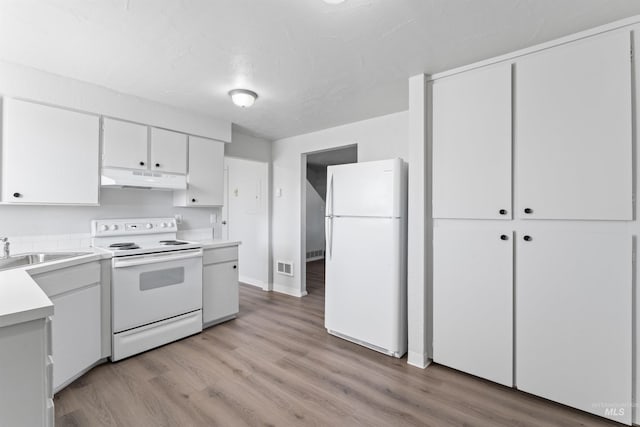 kitchen featuring light countertops, white cabinets, a sink, white appliances, and under cabinet range hood