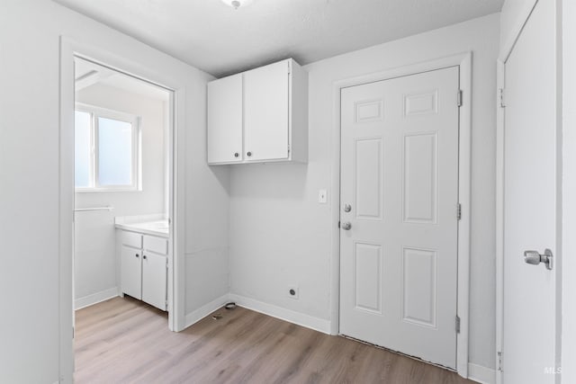 clothes washing area featuring light wood finished floors and baseboards