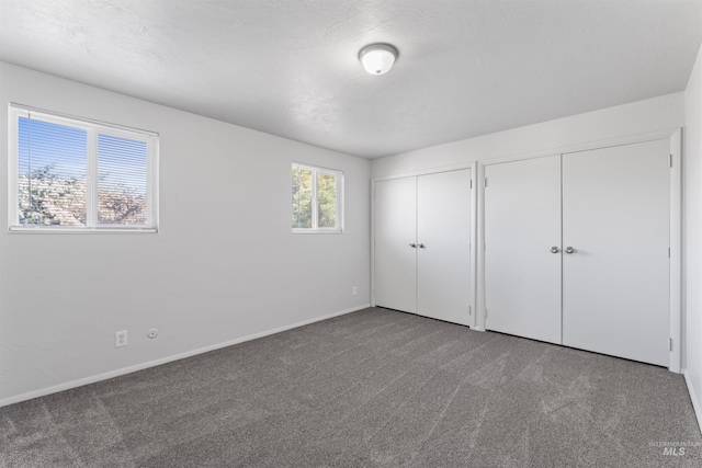 unfurnished bedroom featuring baseboards, two closets, and carpet flooring