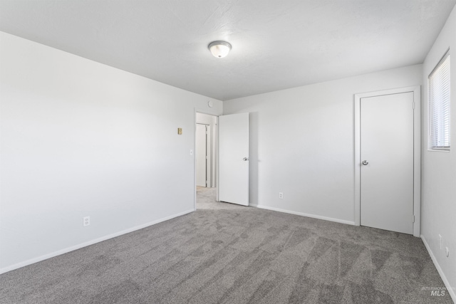 unfurnished bedroom with carpet flooring and baseboards