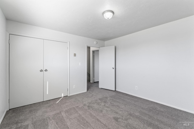 unfurnished bedroom with carpet floors, baseboards, and a closet