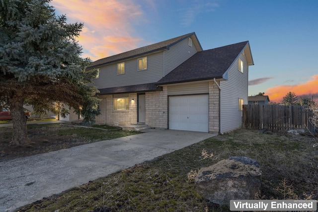 traditional-style home with an attached garage, fence, driveway, roof with shingles, and a front yard