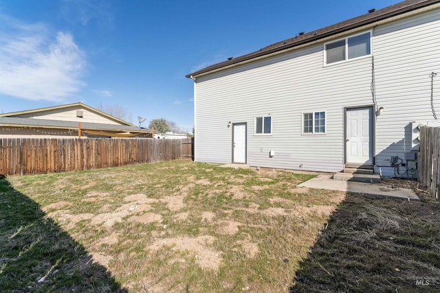 back of property featuring entry steps, fence, and a yard