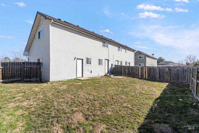 rear view of house featuring a fenced backyard and a lawn